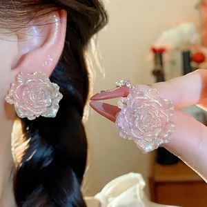 Close-up detail of romantic pink shimmering resin rose flower stud earrings for women
