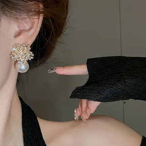 Detail view of elegant sparkling floral crystal earrings with white pearl drop on model