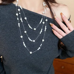 Vista dettagliata di un'elegante collana di perle a tre strati su un maglione grigio