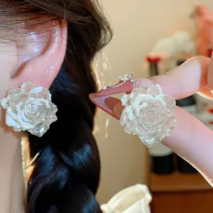 Detailed close-up view of elegant white resin rose stud earrings with silver needles.