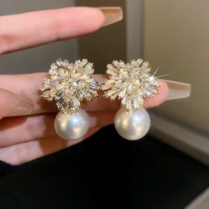 Close-up detail of elegant crystal flower and white pearl earrings with silver needle