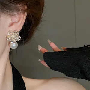 Exquisite close-up of snowflake crystal flower pearl drop earring worn by a model
