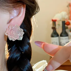 Close-up shot of elegant pink resin rose flower stud earring worn on the ear for detail