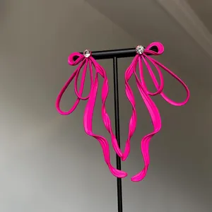 Vibrant pink bow earrings with sparkling crystal centers and hypoallergenic silver studs.