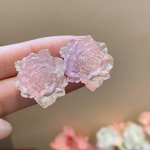 Detailed macro view of pink resin rose stud earrings with shimmering glitter finish