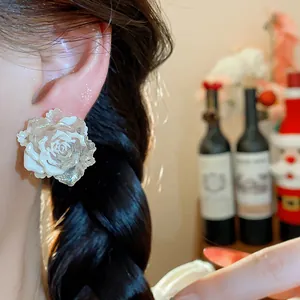 Close-up view of a white resin rose earring with silver needle and subtle glitter finish.