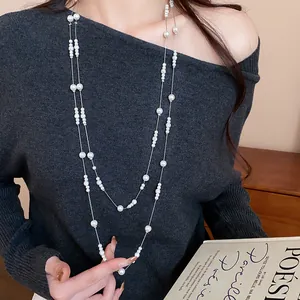 Dettaglio di un'elegante collana di perle lunga a strati, accessorio per maglione minimalista
