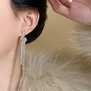 Close-up view of elegant geometric zircon tassel earrings worn by a model in soft light