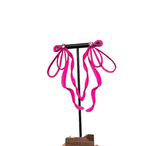 Elegant hot pink oversized bow earrings with rhinestones on a minimalist display stand