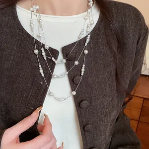 Dettaglio collana di perle multistrato con strass indossata su una giacca marrone