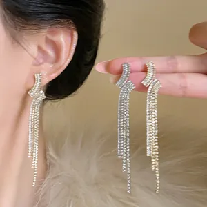 Close-up of geometric tassel earrings with zirconia in gold and silver finishes