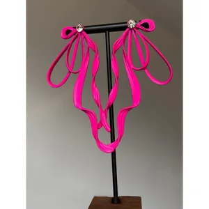 Macro view of elegant neon pink ribbon bow earrings with sparkling rhinestone stud detail