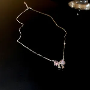 Gros plan détaillé d'un collier en argent avec pendentif nœud en zircon rose scintillant
