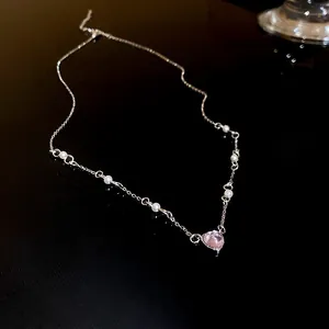 Gros plan d'un collier pendentif cœur en argent avec perles blanches sur fond noir