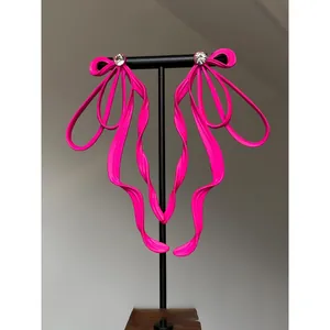Close-up detail of oversized hot pink ribbon bow earrings with sparkling crystal center