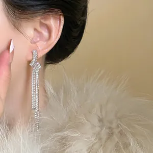 Detailed macro view of elegant silver zircon geometric tassel drop earrings worn by a model