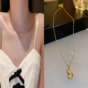Detail of golden windmill pendant necklace with shimmering zircon stones on model.