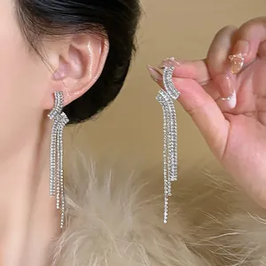 Close-up of elegant silver tassel earrings with sparkling zircons on model