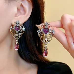 Close-up of vintage heart teardrop hollow earrings with rhinestones and purple stones