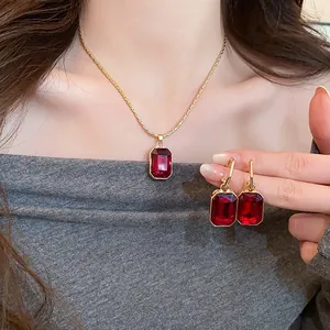 Close-up of gold-plated necklace and earring set with vibrant rectangular red stones