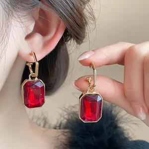 Close-up view of vintage style red rectangular gemstone dangle earrings with a gold finish