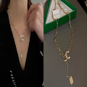 Detailed close-up of a stylish gold chain necklace with a crystal-encrusted CC pendant.