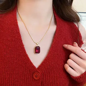 Close-up view of a vintage style red square gemstone pendant on a thin gold chain