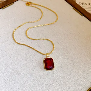 Close-up of a vintage gold necklace featuring a luxury red square gemstone pendant