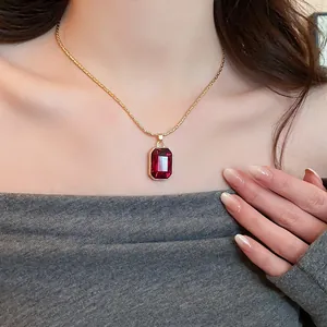 Elegant gold-tone necklace with a striking rectangular red gemstone pendant detail.