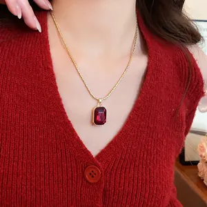 Close-up of an elegant gold necklace with a large emerald-cut red gemstone pendant