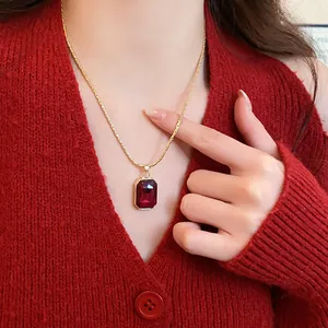 Close-up of a vintage red square gemstone pendant necklace on a red sweater