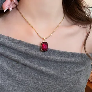 Detail of vintage gold necklace with elegant rectangular red crystal pendant