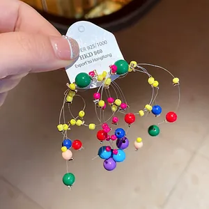 Close-up of vibrant dopamine style colorful beaded tassel earrings on a card