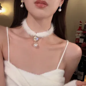 Dettaglio di un choker in pelliccia bianca con fiocco di neve in zircone e perla natalizia.