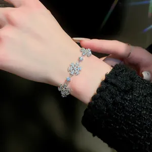 Close-up of a sparkling silver snowflake bracelet with zircon stones on a person's wrist.