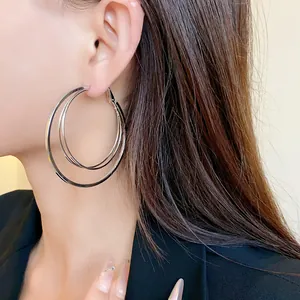 Detail of multi-layer silver hoop earrings with steel needles shown on an ear
