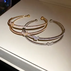 Elegante bracciale aperto a doppio strato con motivi a farfalla in zirconi in oro e argento.