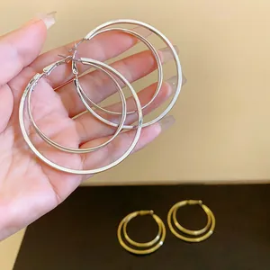 Detailed view of silver-toned multi-layered hoop earrings being held by hand.