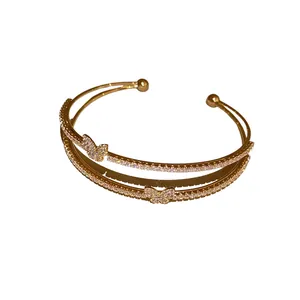 Bracciale rigido a doppio strato placcato oro con farfalle di zirconi su sfondo bianco puro