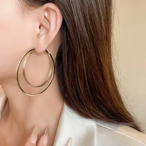 Close-up detail shot of elegant multi-layered gold hoop earrings worn by a female model