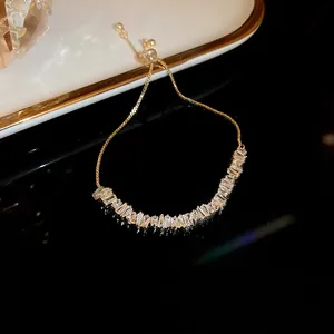 Detail view of gold adjustable bracelet with sparkling baguette-cut zircons on black background