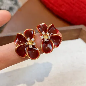 Close-up of elegant Ankara red flower stud earrings with zircon center and gold plating