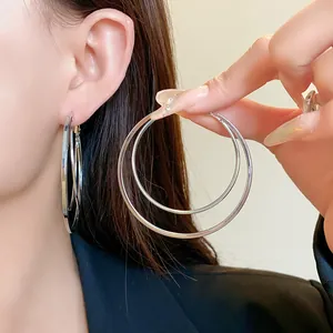 Close-up detail of oversized multi-layer silver hoop earrings showing the layered design