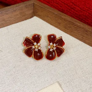 Detailed view of Ancora red flower stud earrings with sparkling zircon stones and gold trim