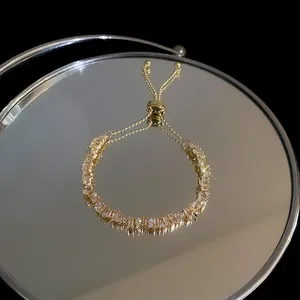 Macro view of an elegant gold bracelet with zircon stones and pearls on a mirror.