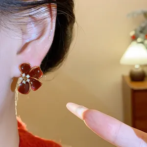 Close-up detail of elegant dark red flower stud earring with zircon center on ear