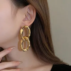Statement irregular gold-tone metal oval link drop earrings displayed on model's ear lobe