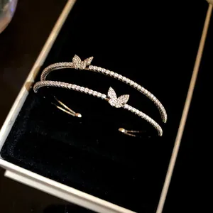 Primo piano di bracciale rigido a doppio strato con farfalle in pavé e scatola