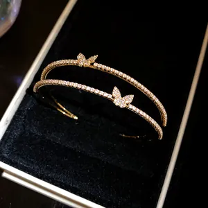 Dettaglio di elegante bracciale rigido dorato a doppio strato con farfalla e pietre di zircone