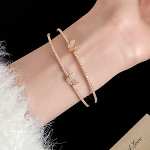 Dettaglio di eleganti bracciali a farfalla dorati con pavé di zirconi luccicanti su polso.